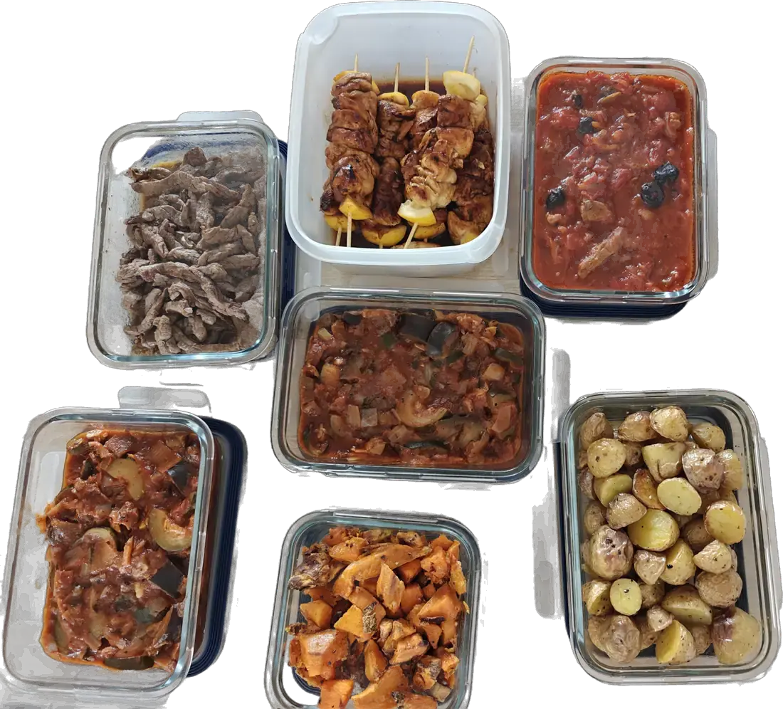 Boîtes en verre remplies de plats faits maison pour la semaine : brochettes, émincé de bœuf, légumes mijotés, patates douces et pommes de terre rôties