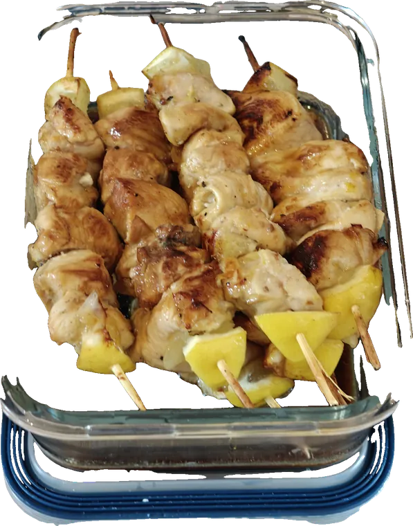 Brochettes de poulet au citron rangées dans une boîte en verre, préparées à l’avance pour un dîner de famille